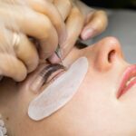 Female face under procedure of eyelashes lamination in beauty salon, closeup